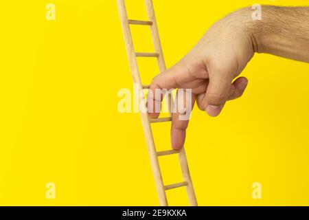 Personal development, career growth and leadership concept. Male fingers climbing upstairs on yellow background Stock Photo