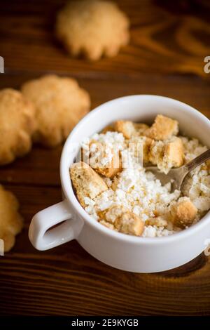 Homemade cottage cheese with pieces of shortbread cookies for breakfast, on a wooden table Stock Photo