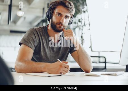 Bearded man freelance worker making notes in his notepad Stock Photo
