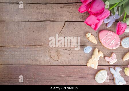 Easter gingerbread cookies, spring flowers and eggs on wooden background. Cozy home Easter greeeting card concept, copy space top view Stock Photo