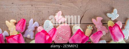 Easter gingerbread cookies, spring flowers and eggs on wooden background. Cozy home Easter greeeting card concept, copy space top view Stock Photo