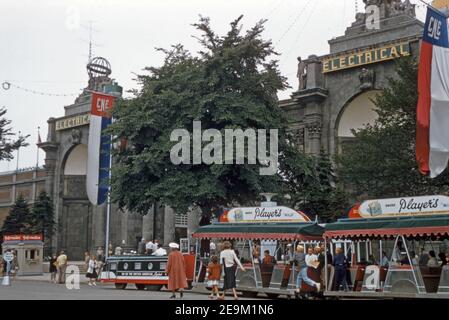 Outside the Engineeering and Electrical Building at Toronto’s CNE in 1957. A ‘train’ waits to take visitors around the site. The Canadian National Exhibition (CNE, The Exhibition or The Ex) is an annual event that takes place at Exhibition Place, located on the shores of Lake Ontario, in Toronto, Ontario, Canada. In desperate need of repair, the Electrical and Engineering Building was demolished in 1972. Stock Photo