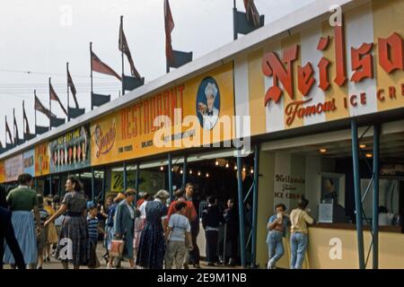 Visitors at the outdoor food outlets at Toronto’s CNE in 1957. Take-away options include Neilson’s ice cream and salads and sandwiches from Singers Restaurant. The Canadian National Exhibition (CNE, The Exhibition or The Ex) is an annual event that takes place at Exhibition Place, located on the shores of Lake Ontario, in Toronto, Ontario, Canada, during the 18 days leading up to and including Canadian Labour Day (the first Monday in September). Stock Photo