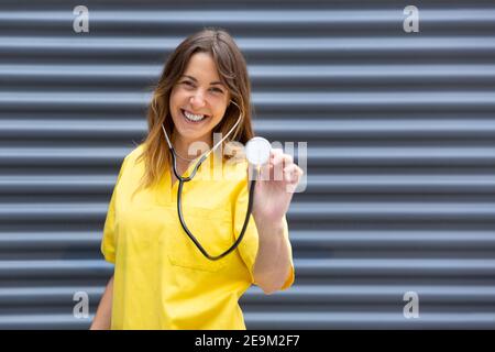 Portrait of smiling young female nurse in uniform using stethoscope. Space for text.