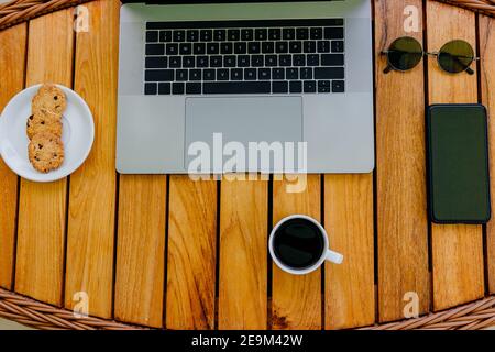 Flat lay. Workspace minimalistic concept with gray modern laptop and smartphone to work on natural wood brown office desk. Time for a coffee break, a Stock Photo