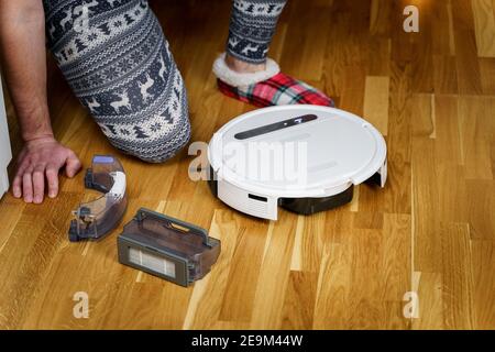 Young caucasian man doing cleaning for the holiday christmas in winter. A male in funny home clothes, pajamas with winter ornament collects and sets Stock Photo