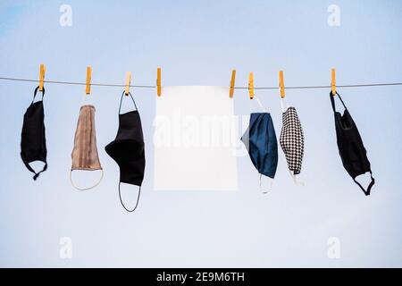 Many protective masks and sheet of paper hanging on the rope Stock Photo