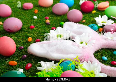 Colored eggs and vibrant candies on grass. Easter composition Stock Photo