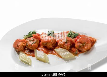 Polpette al Sugo, Italian beef meatballs with tomato sauce with vegetables in white plate isolated on white Stock Photo