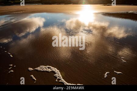 Clouds reflecting off a wet beach on a sunny day Stock Photo