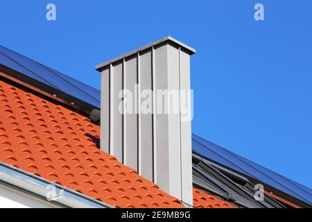 Chimney with stainless steel cladding on a newly covered roof Stock Photo