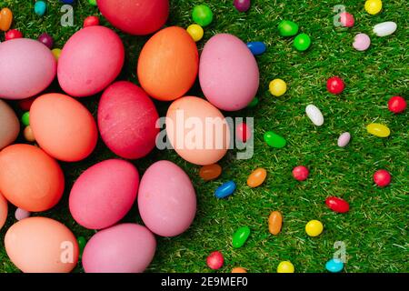 Colored eggs and vibrant candies on grass. Easter composition Stock Photo