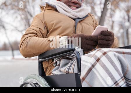 Close-up of disabled man in wheelchair using mobile phone outdoors Stock Photo