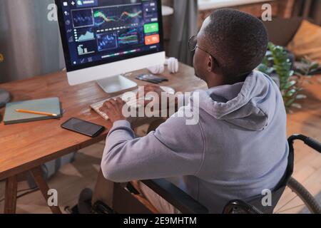 Rear view of African disabled man typing on computer developing new software while working at home Stock Photo
