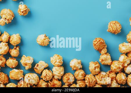 Popcorn is scattered on a blue background, in the form of a frame. Yummy for the filming of movies, TV series, cartoons. Free space, top view Stock Photo