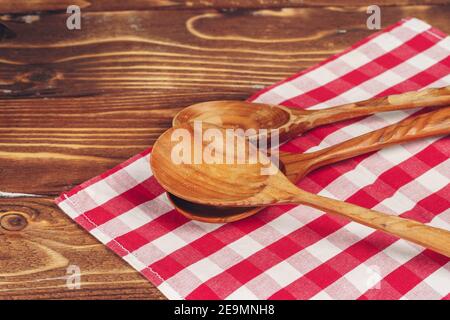 Three wooden spoons on a checkered napkin on kitchen table Stock Photo