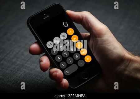 a man using the iPhone calculator on his iPhone Stock Photo