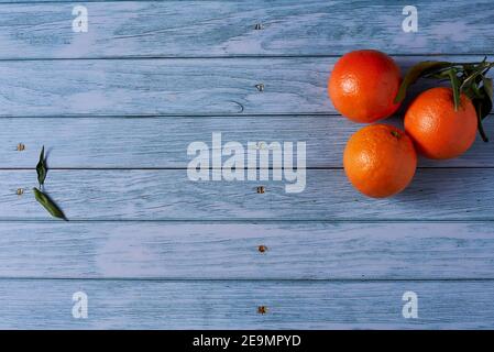 Three oranges on wooden floor with nails, orange leaves, empty space Stock Photo