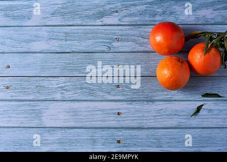 Three oranges on wooden floor with nails, orange leaves, empty space Stock Photo