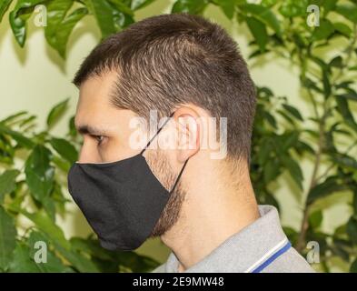 A young man in a black mask - on his back plants. Stock Photo