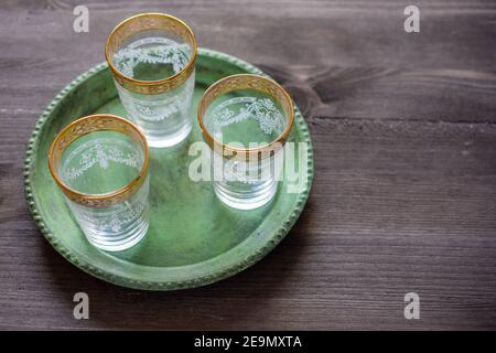 Aerial view of three empty glasses of Arab tea on a green tray, on a rustic wooden table, horizontally, with copy space Stock Photo