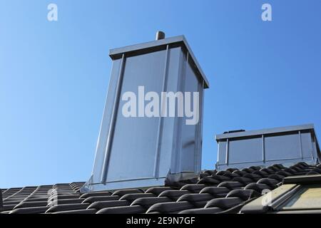 Chimney with stainless steel cladding on a newly covered roof Stock Photo