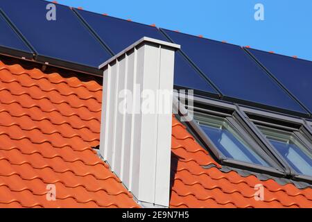 Chimney with stainless steel cladding on a newly covered roof Stock Photo