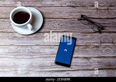 A mobile phone or cell phone laid on a wooden table or desk with the Nord VPN app open Stock Photo