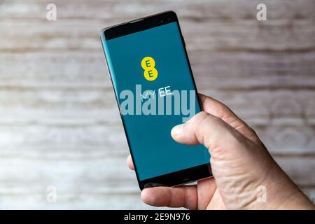 A Mobile phone or cell phone being held showing the EE Mobile app open on screen Stock Photo