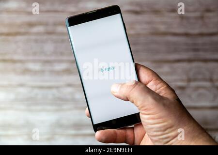 A Mobile phone or cell phone being held showing the Fitbit app open on screen Stock Photo