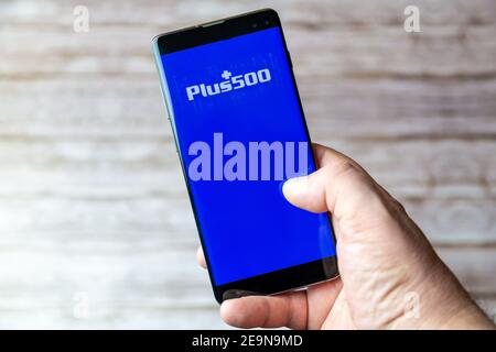 A Mobile phone or cell phone being held showing the Plus 500 trading app open on screen Stock Photo