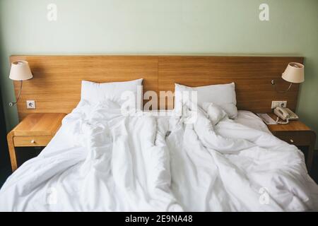 View of a rumpled bed with white pillows and a duvet. Stock Photo