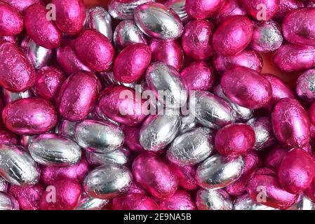 Pink and silver foil wrapped chocolate easter eggs, against a black background. Stock Photo