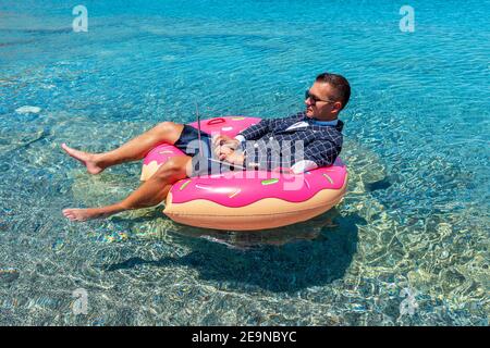 Businessman using laptop computer on an inflatable donut in the sea. Summer vacation concept. Stock Photo
