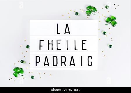 Lightbox with Saint Patricks day text written in irish and green glass shamrocks Stock Photo