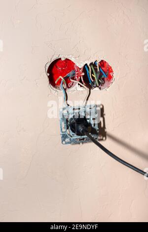 Broken electrical outlet with plug in. Danger of short circuit and fire. Improper use of devices. Stock Photo