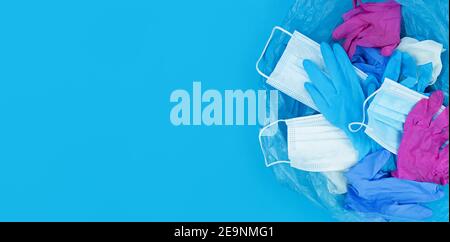 Medical pandemic coronavirus waste, face masks and latex gloves in garbage bag on blue background with copy space. Stock Photo