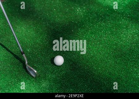 Niblick and white ball for golf on the green grass. Empty right side for text of advert for golf clubs. Stock Photo