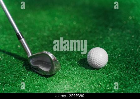 Playing in mini-golf on the green grass using niblick. Player hits white ball. Golf sport game. Advert for golf club Stock Photo