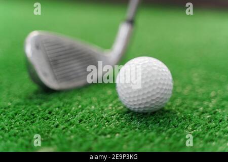 Close-up playing in mini-golf on the green grass using niblick. Player hits white ball. Golf sport game. Advert for golf club Stock Photo