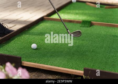 Playing in mini-golf on the green grass using niblick. Player hits white ball. Golf sport game. Advert for golf club Stock Photo