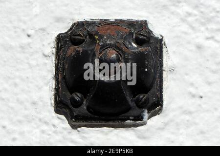 This old doorbell button and its chipping and worn paint and screws, all against a stucco white background, has a lot of mechanical character. Stock Photo