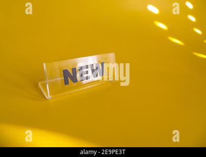 Transparent plastic price tag with black inscription new on a yellow background. Concept for sale or shop Stock Photo