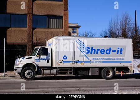 A Shred It truck parked in front of office building where driver is picking up papers to be shredded Stock Photo