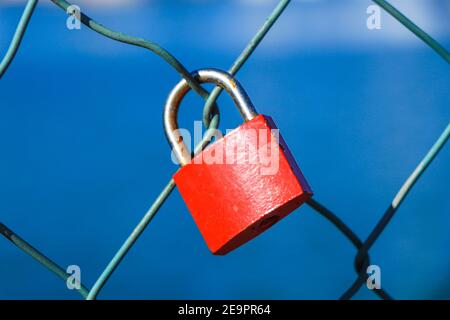 Red padlock in a metal fence Stock Photo