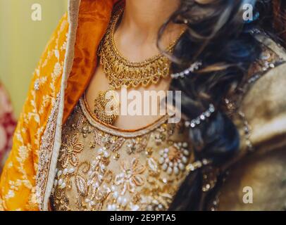 Indian pakistani bride in inlaid yellow festive dress, necklace Stock Photo