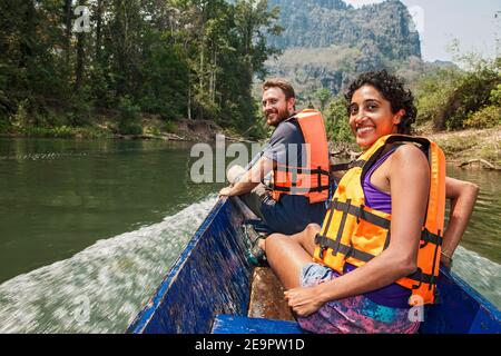 young couple enjoying a ride on a long tail boat in Laos Stock Photo
