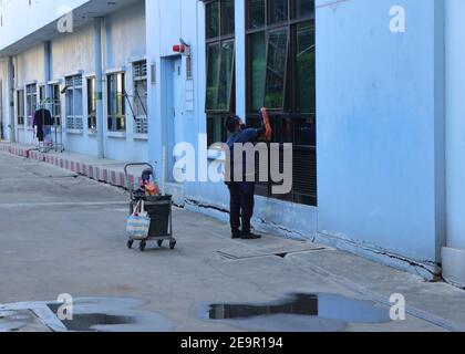 Bangkok, Thailand - February 2, 2021 : Blurred motion of female worker wearing face mask using cloth to clean glass window Stock Photo
