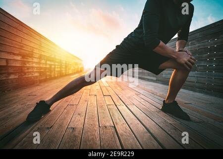 Fitness man stretching legs before workout outdoors. Warming up before running. Sport and healthy lifestyle. Stock Photo