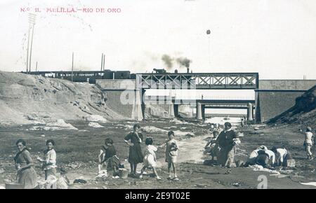 Mujeres lavando al ropa en el Río de Oro, Puente de Hierro de la CEMR, Puente del General Marina y Puente de la CNA, Melilla. Stock Photo